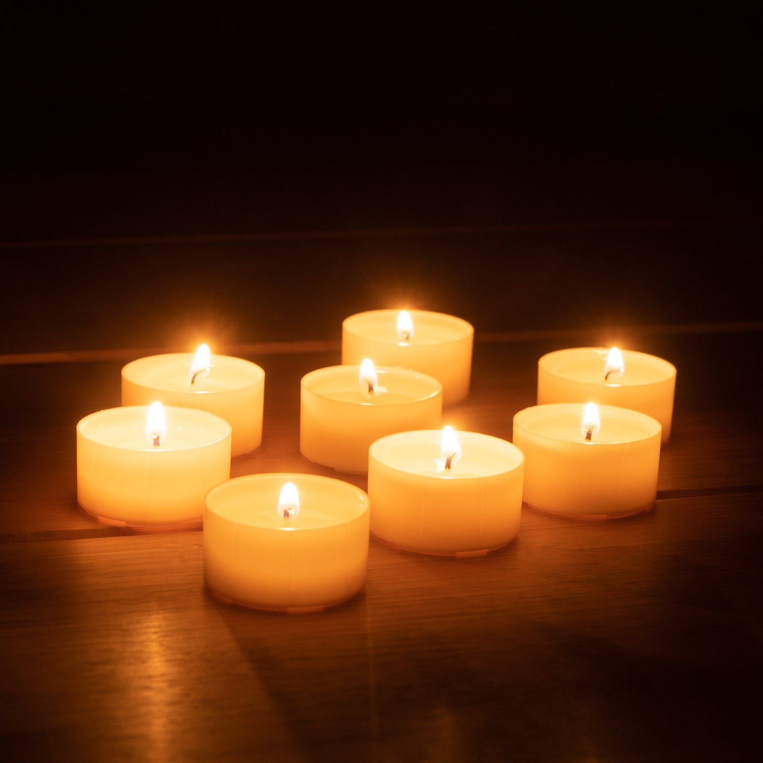 8 Glimmy Teelichter leuchten auf einem Tisch