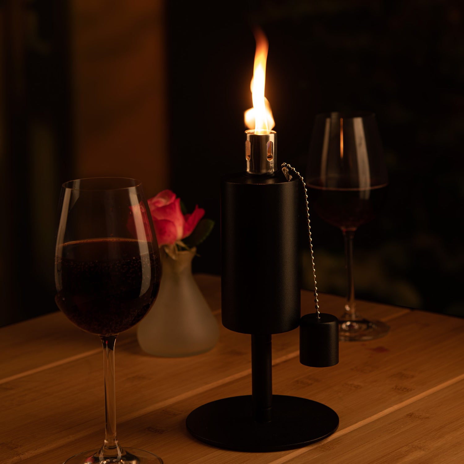 Eine Nachfüllbare Fackel steht auf einem Tisch, daneben ein Rotwein Glas