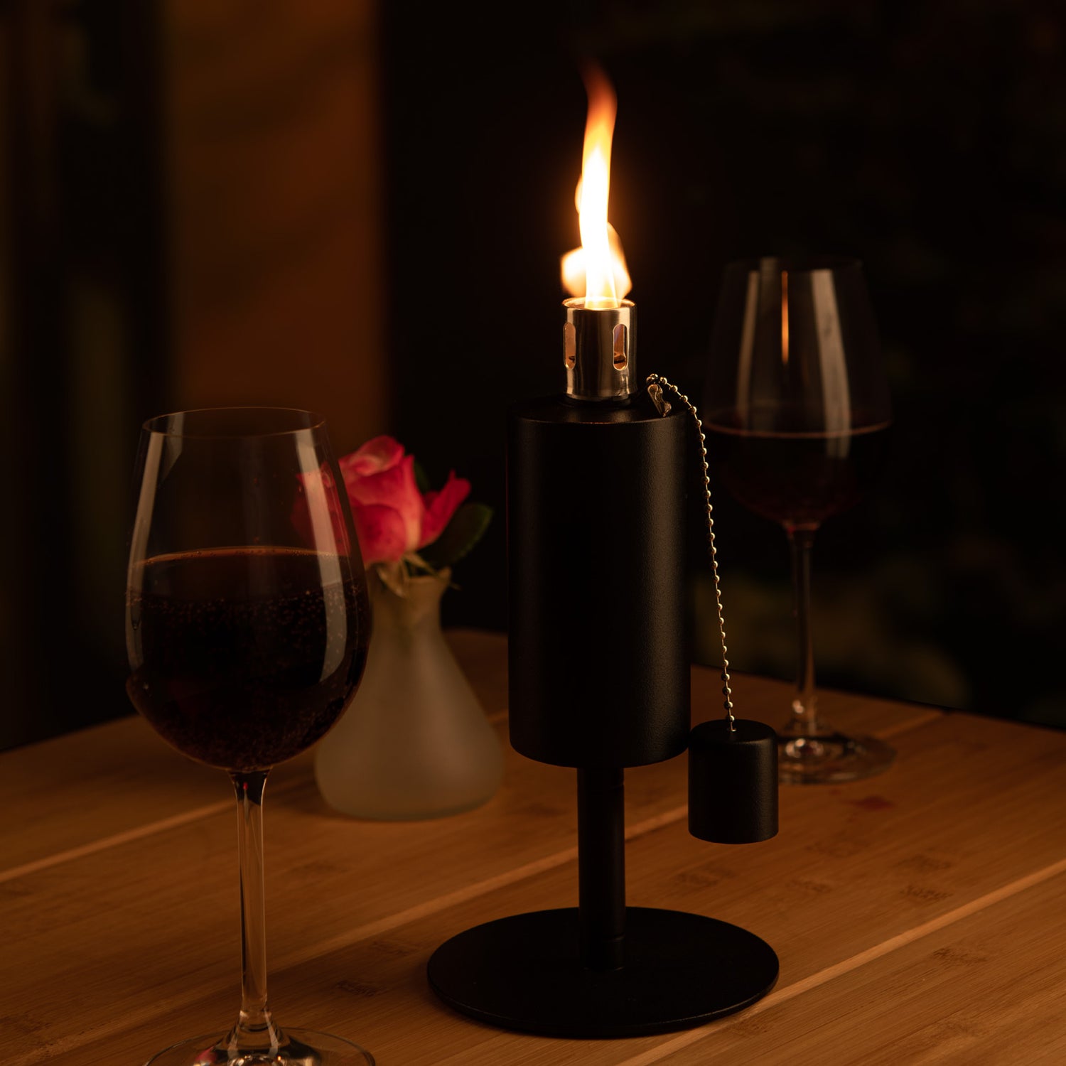 Eine Nachfüllbare Fackel steht auf einem Tisch, daneben ein Rotwein Glas